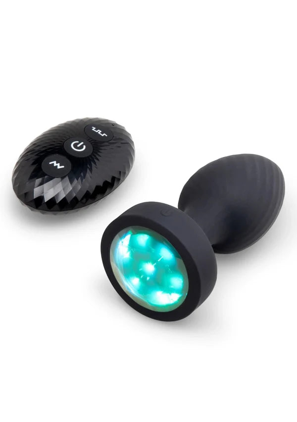 Black dual-in-use wand massager with a textured oval remote control and a bulb-shaped wand head featuring a glowing green LED light ring, shown on a white background.